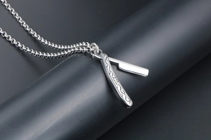 Macro shot of silver stainless steel barber razor pendant with intricate floral engravings