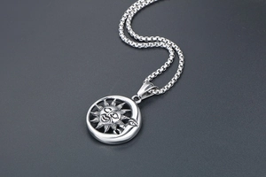 Détail macro du pendentif soleil et lune rétro avec finition oxydée sur chaîne box