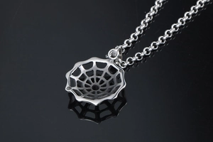 Macro shot of polished silver spider web pendant and stainless steel chain with reflection