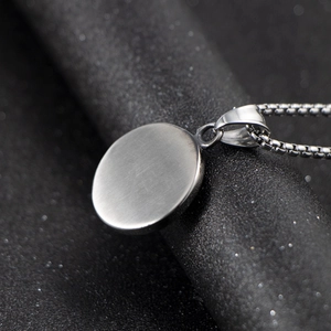 Polished stainless steel round pendant necklace with box chain on dark background
