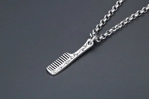 Detailed macro view of a silver comb pendant with intricate floral vine engravings