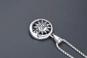 Détail macro du pendentif soleil et lune vintage avec chaîne sur fond sombre