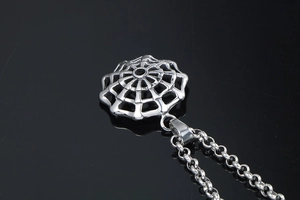Macro shot of polished stainless steel spider web pendant with circular link chain
