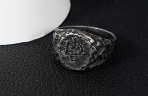 Close-up of vintage oxidized steel ring with irregular lava texture and anchor emblem