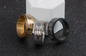 Macro shot of three stainless steel rotating Viking rings with engraved runes in gold, silver and black