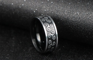 Macro detail of Nordic stainless steel ring with black Celtic triskelion spiral patterns