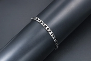 Gros plan d'un bracelet gourmette poli en acier inoxydable sur un support noir