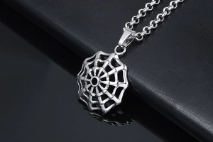 Macro shot of silver titanium spider web pendant on black leather background