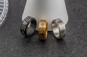 Detailed close-up of Viking runes and Valknut symbols on black, gold, and silver steel rings