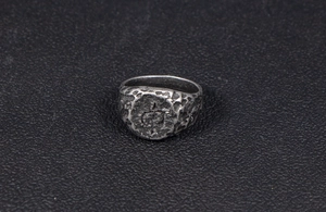 Macro shot of industrial vintage silver ring featuring hammered texture and cross symbol