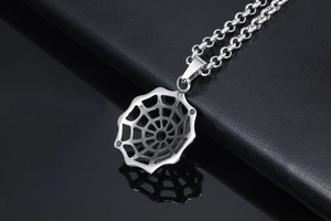 Detailed macro view of a silver spider web pendant with a textured metal chain necklace