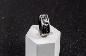 Macro detail of stainless steel ring featuring silver Celtic triskelion spiral patterns