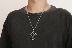 Détail d'un collier pour homme en acier titane avec pendentif croix et insert en cuir