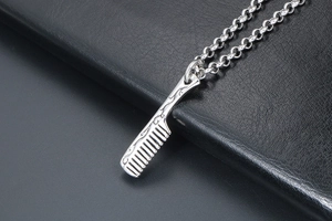 Macro shot of silver titanium steel comb pendant with retro vintage engraved patterns