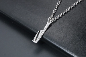 Macro detail of silver comb pendant with intricate floral engravings on a leather background