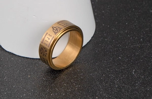 Detailed view of golden rotatable ring with Nordic runes and brushed metal texture