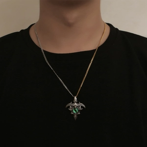 Retro evil eye pendant necklace with green stone and bicolor chain worn by male model