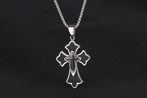 Détail macro du pendentif croix en acier titane avec incrustation noire et chaîne box argent