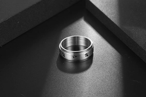 Macro shot of silver spinner ring with turtles on a brushed stainless steel band