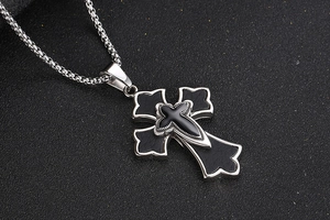 Gros plan d'un pendentif croix en acier titane avec cuir et chaîne à maillons argentée