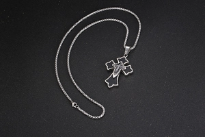 Détail du pendentif croix en acier titane avec cuir de mouton sur une chaîne vénitienne