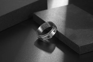 Macro detail of matte stainless steel spinner ring with turtle engravings and brushed finish
