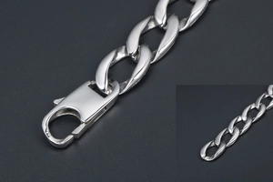 Gros plan sur un bracelet gourmette argenté avec fermoir mousqueton sur fond texturé noir