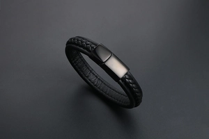 Détail d'un bracelet en cuir tressé noir avec fermoir magnétique en métal brossé