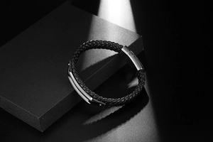 Close-up of men's woven black leather bracelet with polished silver metal buckle