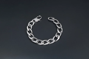 Gros plan d'un bracelet gourmette punk argenté avec fermoir mousqueton sur fond noir