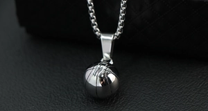 Macro d'un pendentif basket en acier poli avec chaîne sur un fond en cuir texturé noir