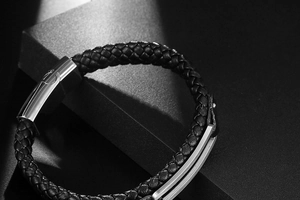 Close-up of black braided leather men's bracelet with polished silver steel buckle