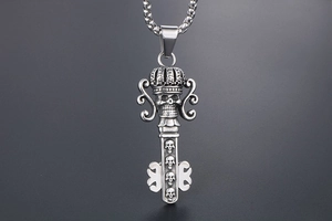 Detail of vintage gothic key pendant with crown and skull motifs in aged silver finish