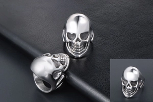 Macro view of polished silver skull ring with realistic bone and teeth detail on black base