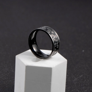 Nordic black stainless steel ring with engraved triple spiral patterns on white pedestal