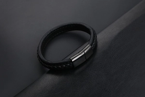 Gros plan d'un bracelet en cuir tressé noir avec fermoir magnétique en métal mat