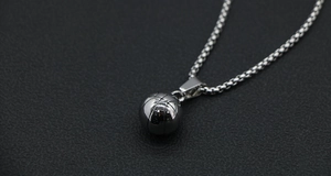Vue macro du pendentif de basket en acier inoxydable argenté avec gravure de couture