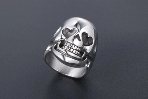 Detail of vintage punk skull ring featuring heart-shaped eye sockets and silver finish