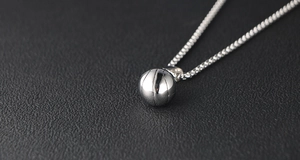 Vue macro du pendentif de basket argenté avec chaîne box sur cuir noir élégant