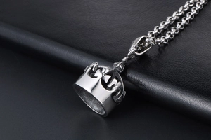 Détail macro du pendentif couronne avec chaîne rolo sur fond de cuir noir