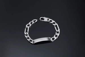 Detailed macro of polished stainless steel Figaro chain bracelet with center ID plaque
