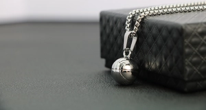 Gros plan du pendentif basket de style NBA sur son coffret à bijoux en cuir noir