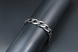 Gros plan d'un bracelet à mailles cubaines en argent poli sur un support gris moderne