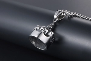 Gros plan d'un pendentif couronne vintage en acier titane avec gravures sur une chaîne à billes