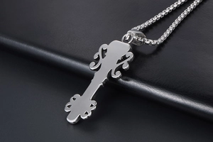 Close-up of vintage crown skull pendant with silver box chain on black leather background
