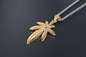 Gros plan d'un pendentif feuille d'érable dorée avec nervures sur chaîne en acier inoxydable