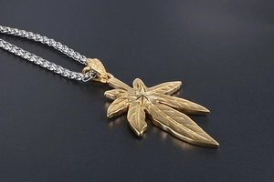 Gros plan du pendentif feuille d'érable dorée sur une épaisse chaîne dragon argentée