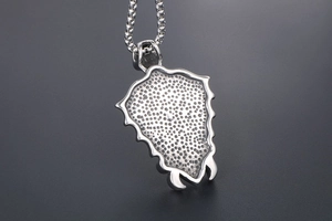 Macro shot showing textured shield pendant back and sturdy box chain in retro silver steel