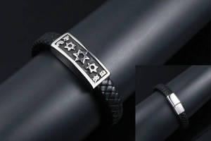 Detail of woven black leather bracelet featuring engraved stars on a silver metal plaque
