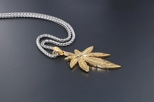 Macro d'un pendentif feuille d'érable dorée avec nervures sur une chaîne en blé argentée